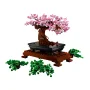 LEGO-Bonsai mit rosa Blüten auf schwarzem Tablett und brauner Basis, lose grüne Laubteile sichtbar