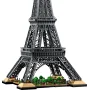 Dunkelgraue LEGO Eiffelturm-Konstruktion mit beiger Basis und kleinen grünen Bäumen am Fuß, Gesamtansicht auf weißem Hintergrund