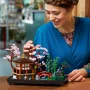 Lächelnde Frau justiert rosa Kirschblütenbaum am LEGO-Modell des friedlichen Gartens mit Pavillon und roter Brücke Lächelnde Frau justiert rosa Kirschblütenbaum am LEGO-Modell des friedlichen Gartens mit Pavillon und roter Brücke