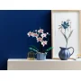 LEGO-Orchidee mit rosa und weißen Blüten in blau gestreiftem Topf auf weißem Regal vor blauer Wand LEGO-Orchidee mit rosa und weißen Blüten in blau gestreiftem Topf auf weißem Regal vor blauer Wand
