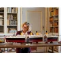 Frau bewundert zusammengebautes LEGO Titanic-Modell auf Schreibtisch in Bibliothek, Schiff mit 4 gelben Schornsteinen