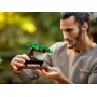 Homme tenant délicatement dans ses mains le bonsaï LEGO avec feuillage vert et tronc marron sur support en bois Homme tenant délicatement dans ses mains le bonsaï LEGO avec feuillage vert et tronc marron sur support en bois