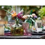 Bouquet LEGO coloré avec roses, gerberas et lavande dans un vase vert sur une table décorée avec verres et bougies Bouquet LEGO coloré avec roses, gerberas et lavande dans un vase vert sur une table décorée avec verres et bougies