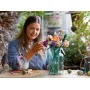 Femme assemblant le bouquet LEGO avec des fleurs colorées dans un vase en verre turquoise sur une table en bois Femme assemblant le bouquet LEGO avec des fleurs colorées dans un vase en verre turquoise sur une table en bois