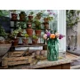 Bouquet LEGO coloré dans un vase vert transparent posé sur une table en bois dans une serre avec des plantes en pots Bouquet LEGO coloré dans un vase vert transparent posé sur une table en bois dans une serre avec des plantes en pots