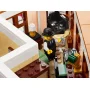 Vue intérieure de l'hôtel LEGO avec réceptionniste en costume à l'accueil, escalier blanc et mobilier détaillé