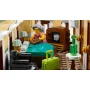 Intérieur de l'hôtel-boutique LEGO avec une réceptionniste aux cheveux gris derrière le comptoir, caisse enregistreuse et bagages verts