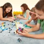 Quatre enfants construisent ensemble sur un tapis avec des briques LEGO colorées, boîte de rangement jaune visible en arrière-plan