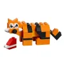 Renard LEGO orange et noir avec rayures, yeux blancs et nez gris, accompagné d'une petite construction rouge et blanche