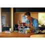 Un homme assemble le set LEGO Le club de jazz sur une table, tenant le toit rouge du bâtiment modulaire avec façades colorées Un homme assemble le set LEGO Le club de jazz sur une table, tenant le toit rouge du bâtiment modulaire avec façades colorées