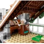 Elrond aux cheveux blancs assis à son bureau en bois sous un toit orné, lisant un livre dans l'architecture elfique de Fondcombe