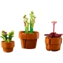 Trois pots de fleurs LEGO avec plantes : un cactus violet, des tiges carnivores vertes et une fleur rose sur tige rouge