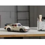 Modèle LEGO Porsche 911 blanc cassé avec aileron noir posé sur un bureau en bois à côté d'un pot à crayons