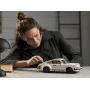 Femme assemblant la Porsche 911 LEGO blanche sur un bureau, se penchant pour ajuster les détails du modèle