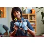 Femme souriante tenant le modèle LEGO Vespa 125 bleu clair avec une minifigurine assise dessus dans un intérieur moderne