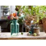 Colorful LEGO flower bouquet in turquoise glass vase on wooden table with twine spool and scissors