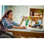 Young girl arranging colorful LEGO flowers in a clear vase on a kitchen table Young girl arranging colorful LEGO flowers in a clear vase on a kitchen table