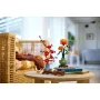 Orange LEGO chrysanthemum in green vase on round table with cherry blossom branch, books and origami in bright living room