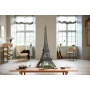 Assembled black LEGO Eiffel Tower model displayed on wooden table in modern living room with windows and furniture