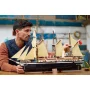 Man admiring the LEGO Endurance ship with three masts, beige sails and detailed black hull on a table