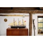 LEGO Endurance ship with black hull and beige sails displayed on wooden cabinet in rustic interior with exposed beams