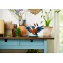 LEGO kingfisher with spread blue wings holding a fish, displayed on shelf with plants and decorative pots LEGO kingfisher with spread blue wings holding a fish, displayed on shelf with plants and decorative pots