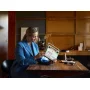 Woman in blue blazer holding a white and orange LEGO retro radio in a modern living room with wooden bookshelf Woman in blue blazer holding a white and orange LEGO retro radio in a modern living room with wooden bookshelf