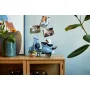 Light blue LEGO Vespa scooter with minifigure displayed on wooden furniture in modern setting with plants and photos