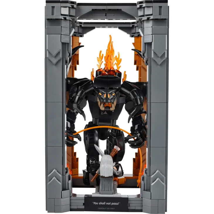 Vista general del Balrog LEGO negro con látigo y llamas naranjas en portal de piedra gris, Gandalf con túnicas grises en primer plano