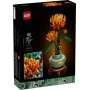 Caja LEGO mostrando un crisantemo naranja construido con ladrillos y tallo verde en maceta sobre fondo negro