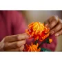 Primer plano de manos sosteniendo delicadamente una flor LEGO crisantemo naranja y roja con pétalos detallados