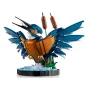 Martín pescador LEGO con alas azules desplegadas, vientre naranja, sosteniendo dos peces, posado en base con vegetación acuática