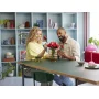Pareja construyendo rosas LEGO rojas en un jarrón sobre una mesa en salón moderno con estantería