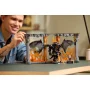 Hombre sonriente sosteniendo Book Nook LEGO del Balrog con llamas naranjas, alas desplegadas y arquitectura gótica detallada
