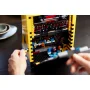 Primer plano de la máquina arcade LEGO PAC-MAN con pantalla negra pixelada, joystick y minifiguras coloridas, manos jugando