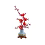 Rama de ciruelo LEGO con flores rojas y capullos rosas en jarrón azul y amarillo sobre base de madera