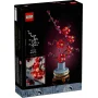 Caja LEGO 10369 mostrando flores de ciruelo rosas y rojas en jarrón azul sobre fondo negro