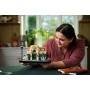 Donna che ammira il set LEGO Café francese assemblato con facciata beige, tenda verde e minifigure in cucina moderna