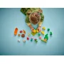 Bambino che gioca con elementi del set LEGO camping: tenda verde, minifigure, falò e accessori colorati