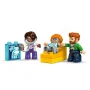 Tre personaggi LEGO DUPLO: dottoressa in camice viola, bambino riccio su tavolo giallo e papà con la barba
