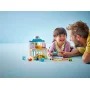 Padre e figlia giocano con set LEGO studio medico a due piani con figure di dottore e paziente su sfondo azzurro