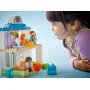 Bambina che gioca con ambulatorio medico LEGO DUPLO, figure di dottore e animali pazienti visibili in edificio bianco e blu