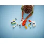 Kind speelt met rode en witte LEGO ambulance, poppetjes, kleurrijk huis en accessoires op blauwe achtergrond