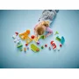 Kind speelt met LEGO kermis-set: geel reuzenrad, kleurrijke attracties, poppetjes en bouwelementen verspreid