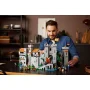 Glimlachende man die LEGO-kasteel bouwt met grijze torens, muren en ridder-minifiguren op een tafel
