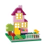 Roze en geel LEGO huis met twee verdiepingen, paars dak, groene boom, wit hekje en kleurrijke bloemen op groene bouwplaat