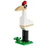 LEGO ooievaar gebouwd met witte stenen, beige snavel, rode kuif en zwarte poten op groene basis met bloemen