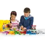 Twee kinderen spelen met kleurrijke LEGO-stenen en bouwen een roze huis en kasteel. Gele LEGO Classic doos zichtbaar.