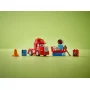 Rode LEGO Mack-truck met blauwe racestand, oranje kegel, band en accessoires op groene achtergrond