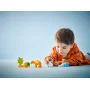 Kind in oranje hoodie speelt met LEGO-stenen met pinguïns, leeuwen en kleurrijke elementen op blauwe achtergrond Kind in oranje hoodie speelt met LEGO-stenen met pinguïns, leeuwen en kleurrijke elementen op blauwe achtergrond